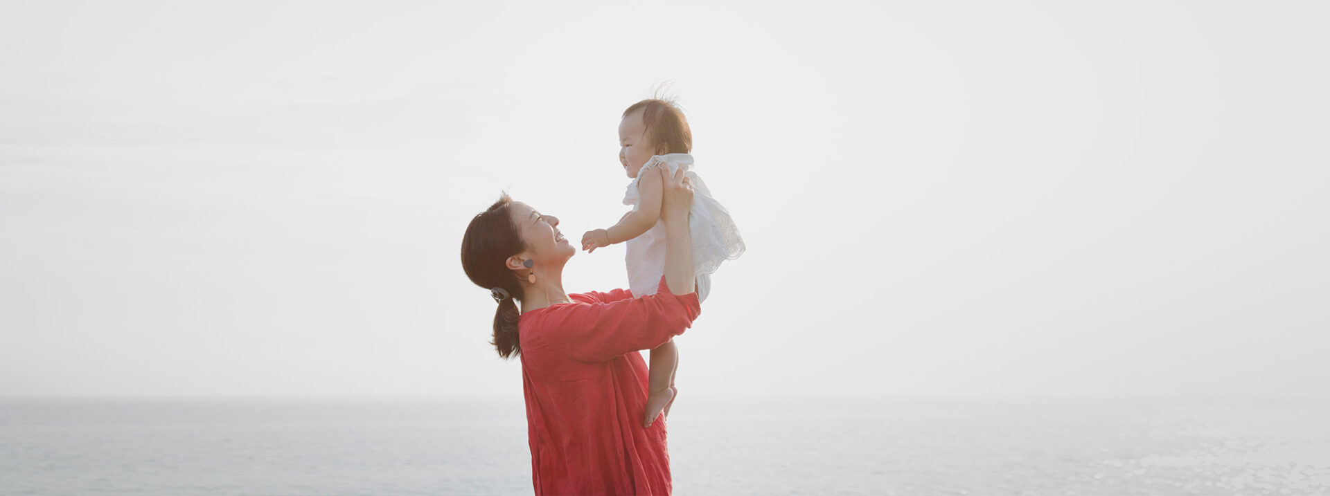 Asian mother holding her daughter at seaside.